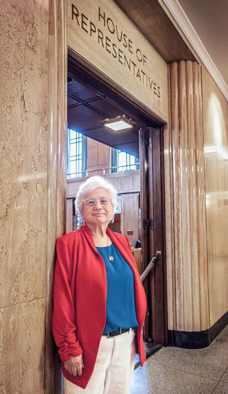 Anna Munson in a red jacket standing in the doorway of the Oregon House of Representatives chamber